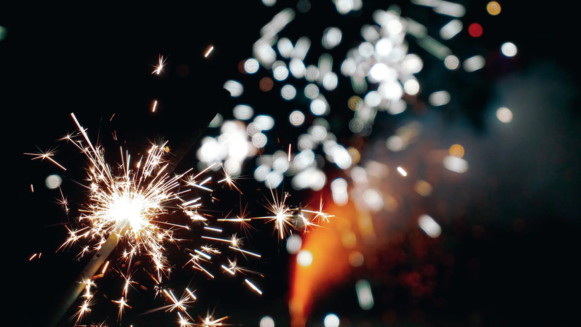 Brennende Wunderkerze vor Feuerwerk
